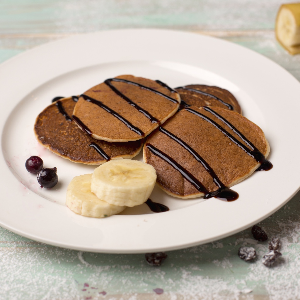 Румяные оладьи с бананом на белой тарелке 