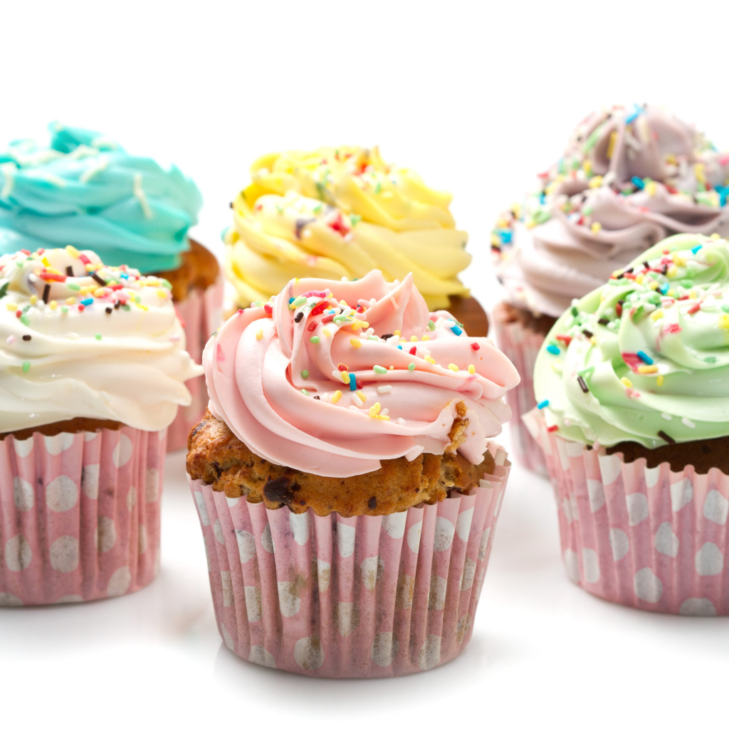 Сладкие кексы с кремом и посыпкой на белом фоне