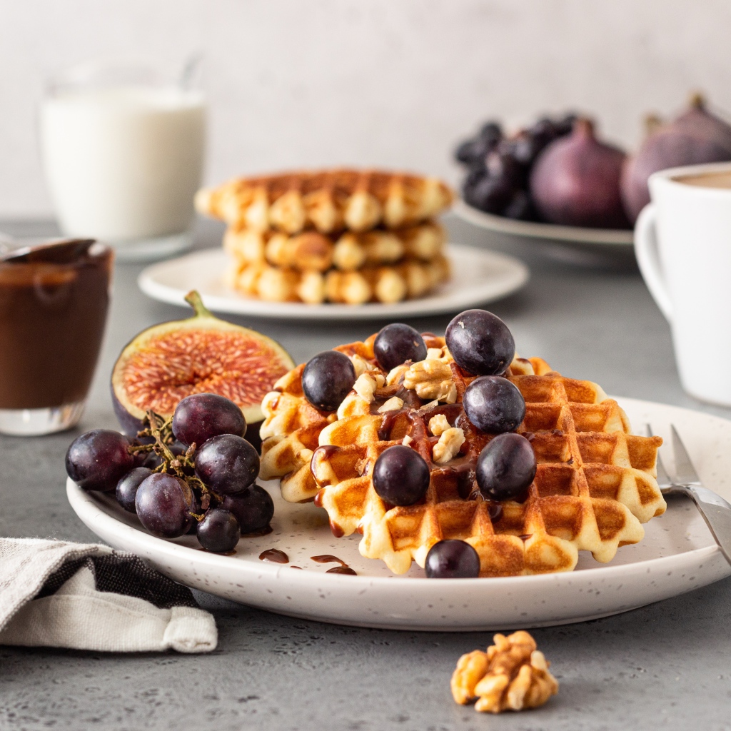 Сладкие вафли на тарелке с инжиром и виноградом