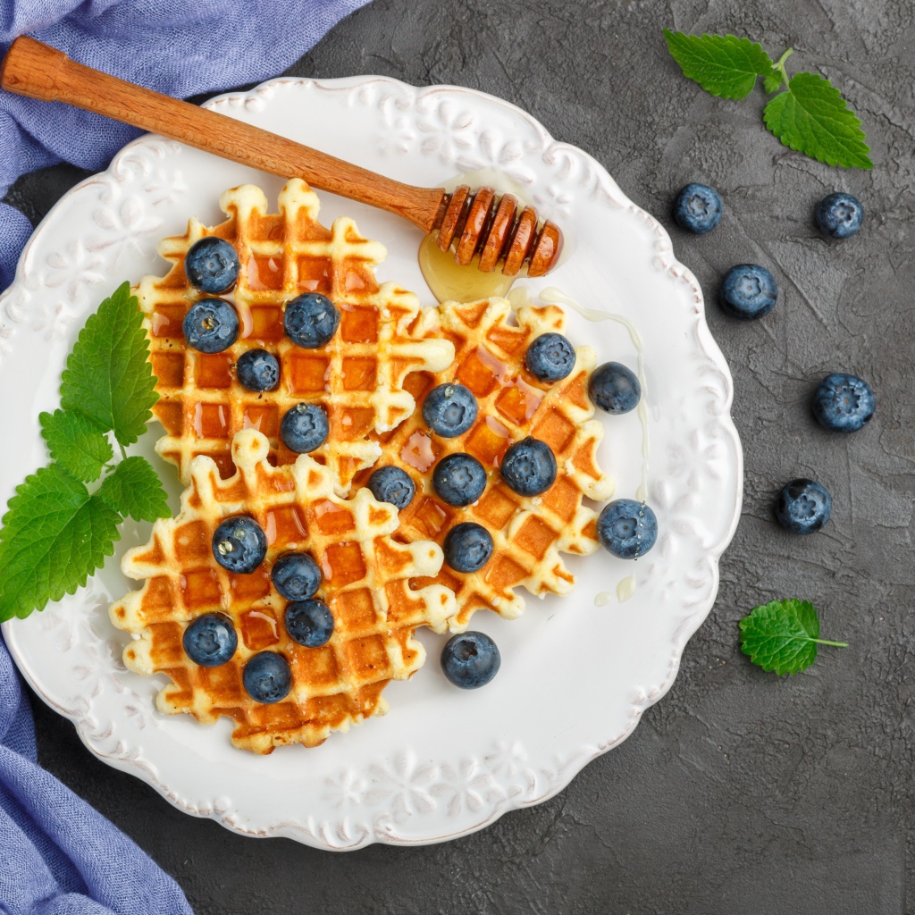 Сладкие вафли с медом на тарелке с ягодами черники