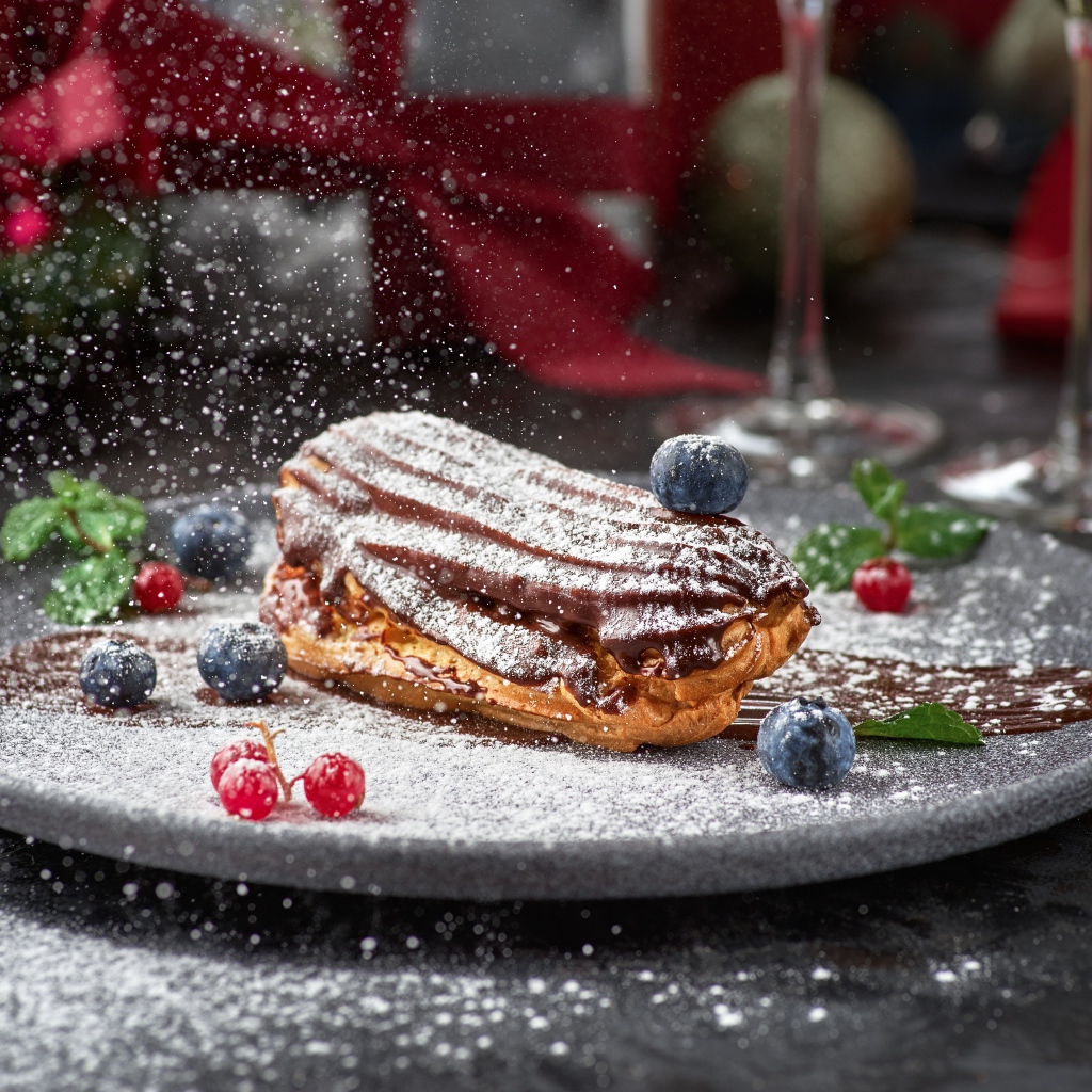Вкусное пирожное на тарелке с сахарной пудрой и ягодами