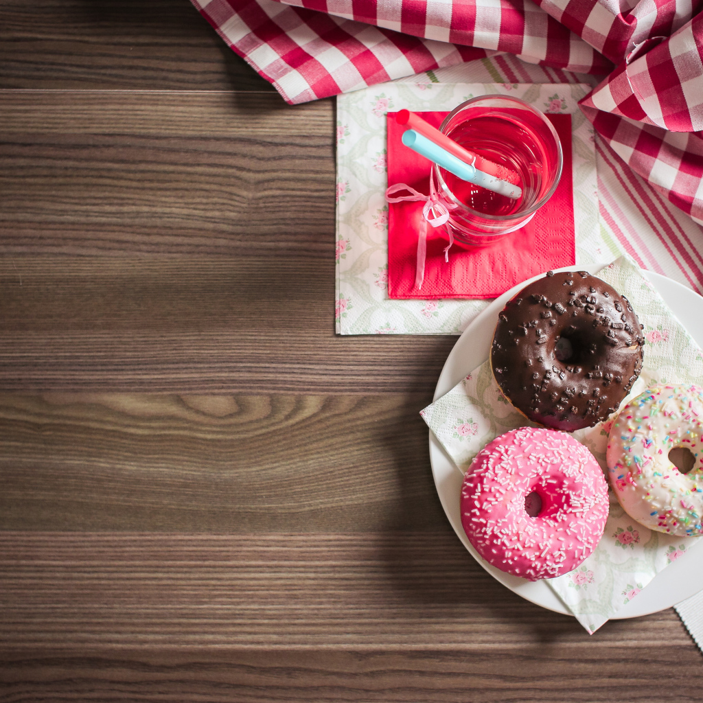 Три сладких пончика с глазурью на столе с лимонадом