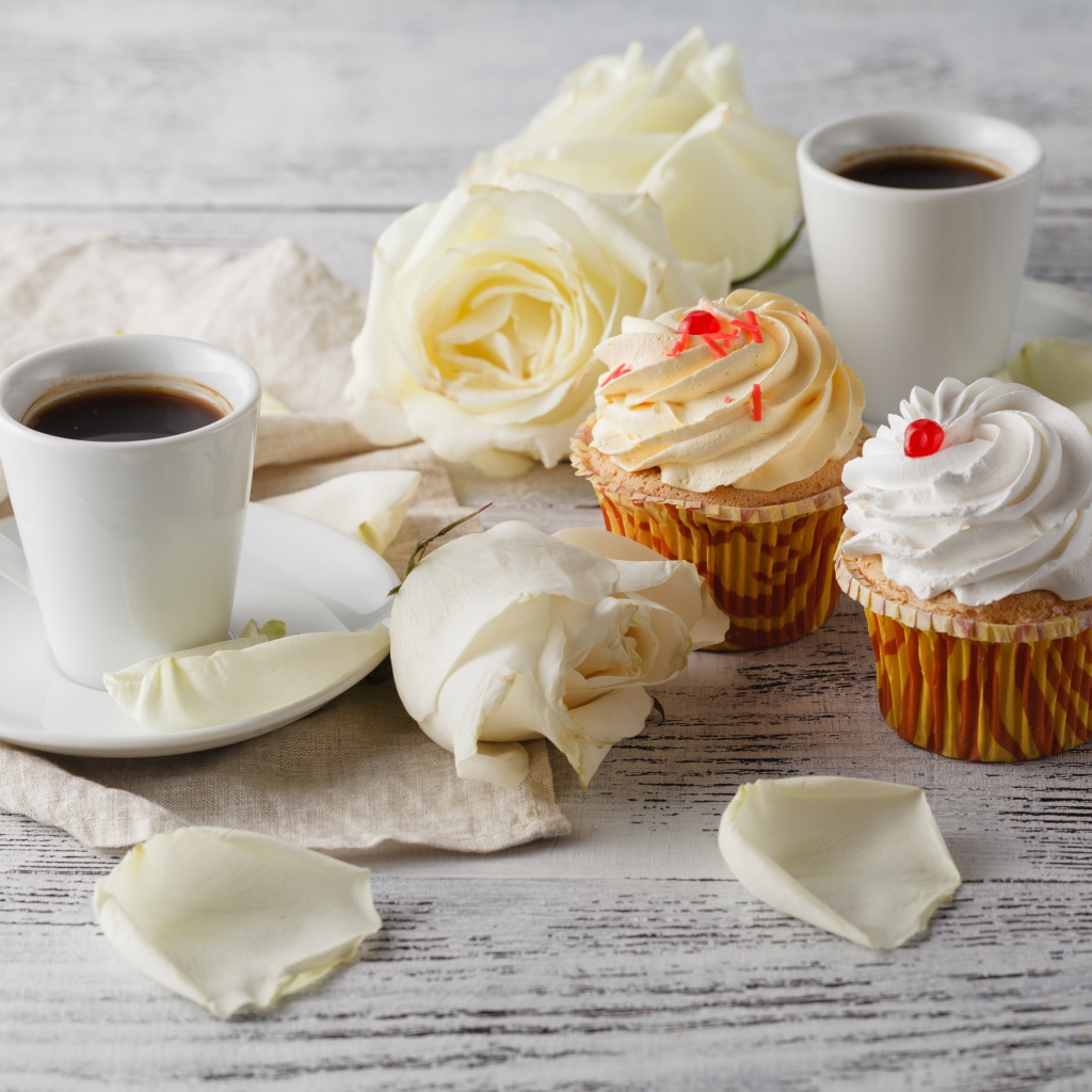 Две чашки кофе на столе с белыми розами и кексами