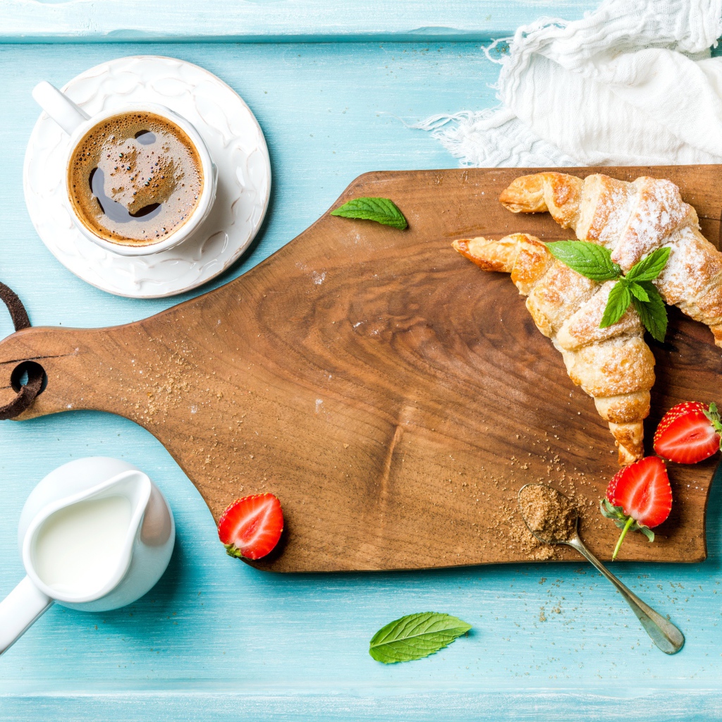 Wooden board on table with croissants and a cup of coffee