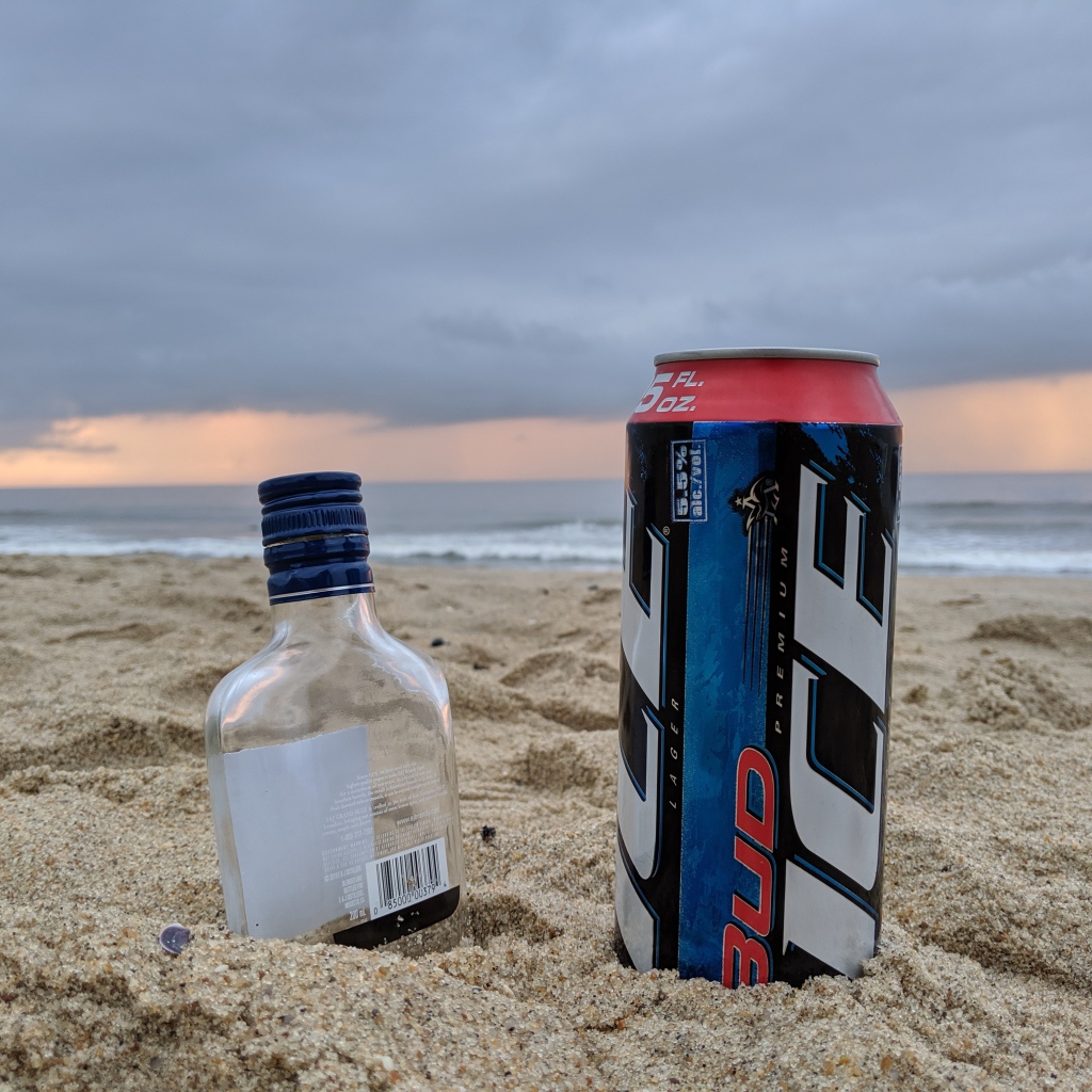 Бутылка пива и бутылка водки на песке у моря