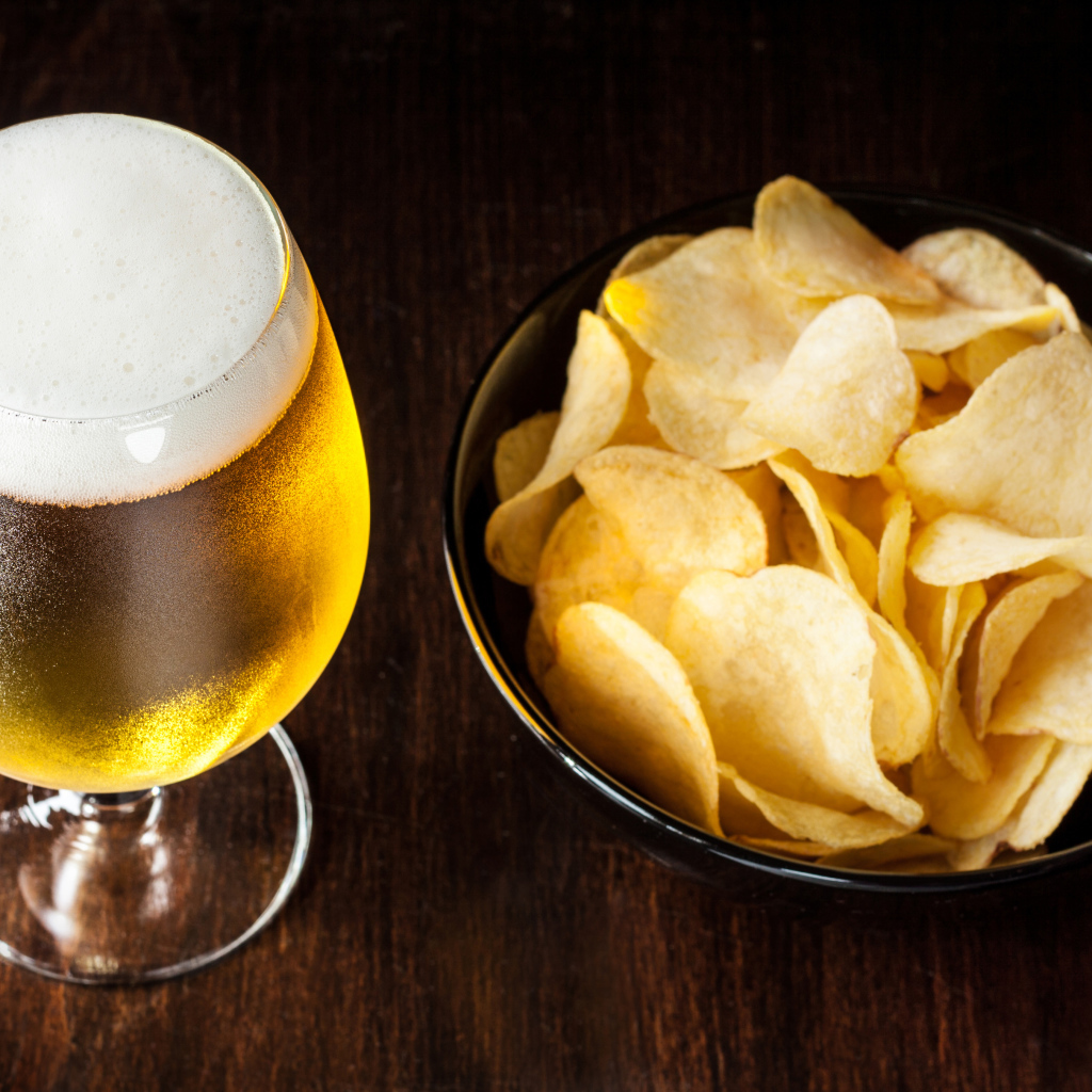 Миска с чипсами на столе с бокалом пива 