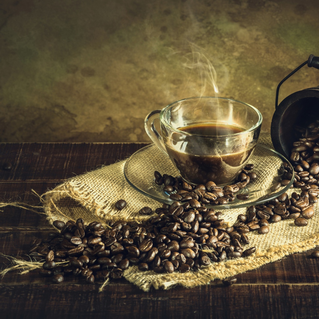 Чашка горячего крепкого кофе на столе с зернами