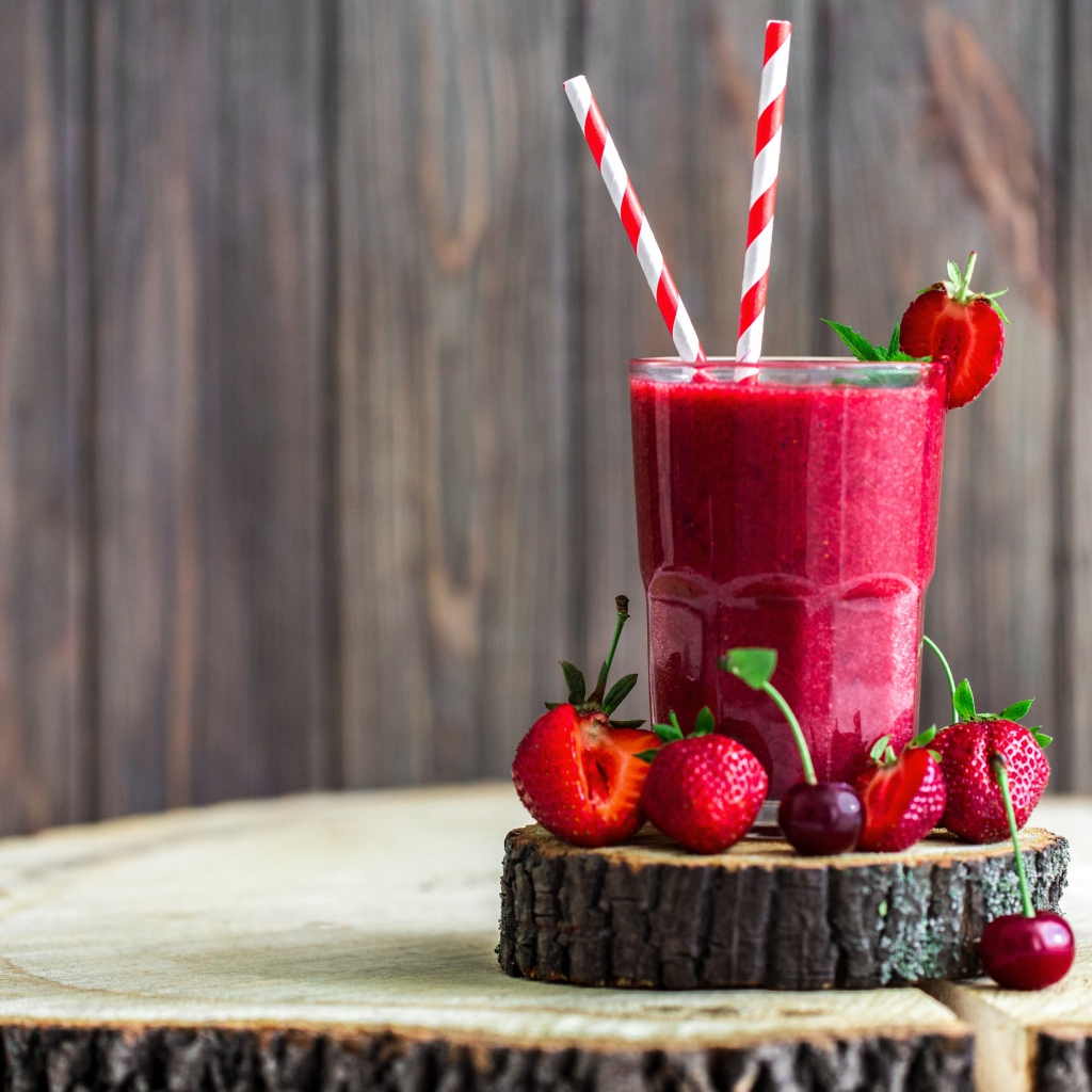Стакан ягодного смузи на столе с клубникой и вишней