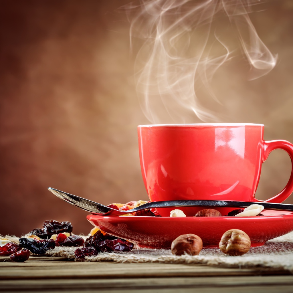 Ароматное горячее кофе в красной чашке на столе с сухофруктами