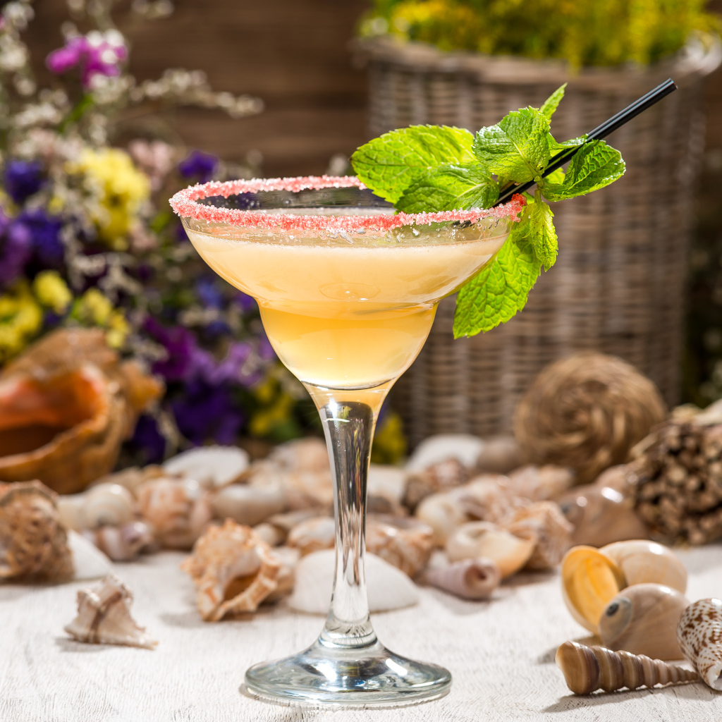 Коктейль с мятой в бокале на столе с ракушками 