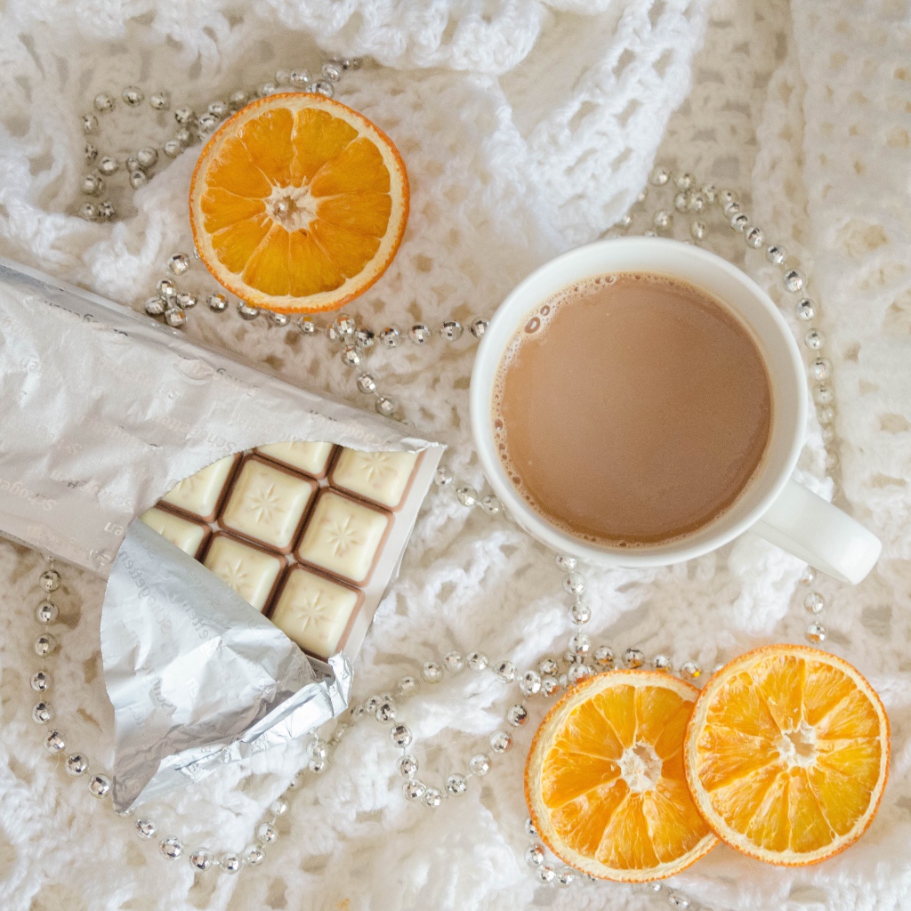 Чашка какао, шоколад и апельсин на белом пледе