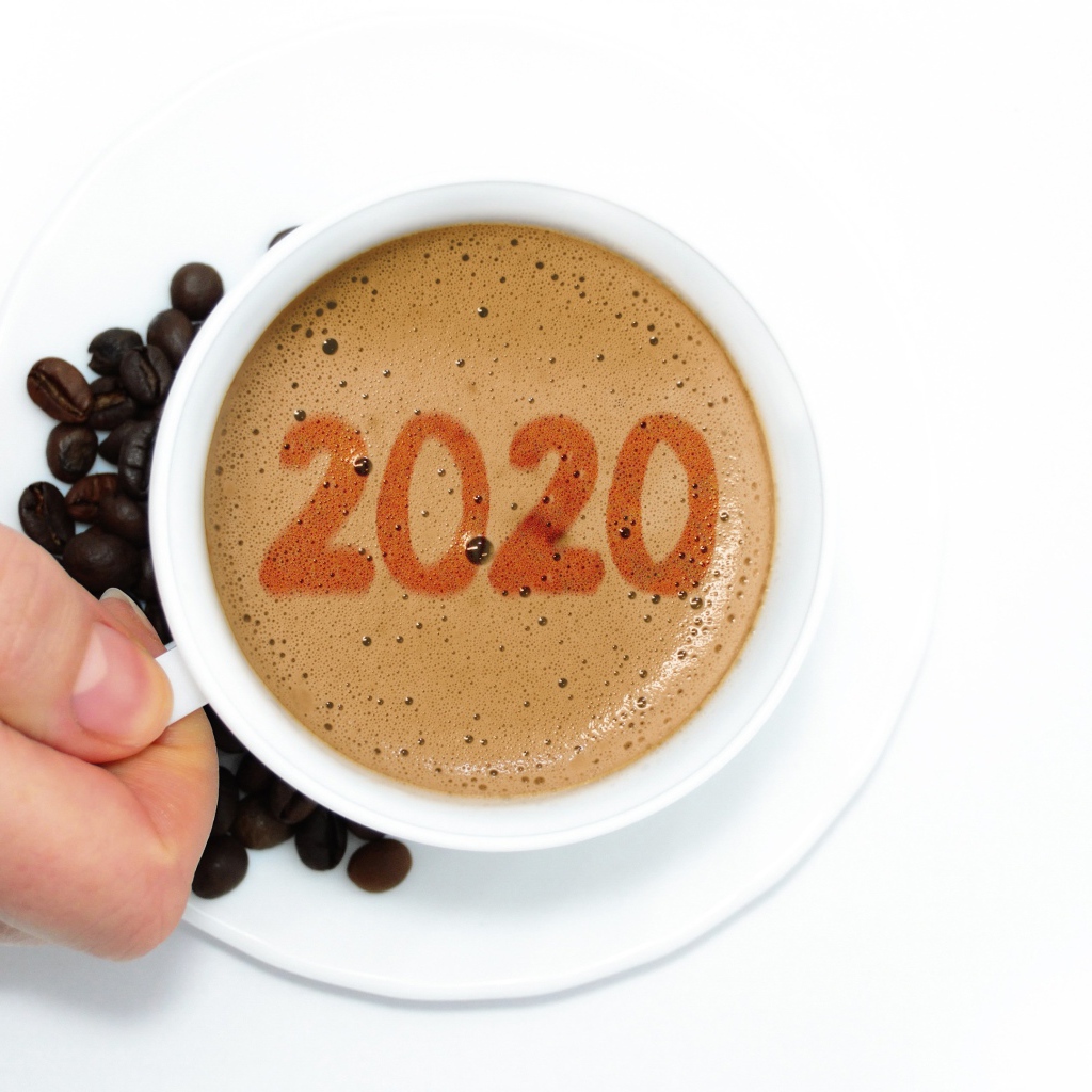 Чашка кофе в руке на белом столе с зернами