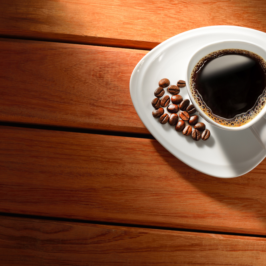 Чашка кофе на тарелке с зернами на деревянном столе