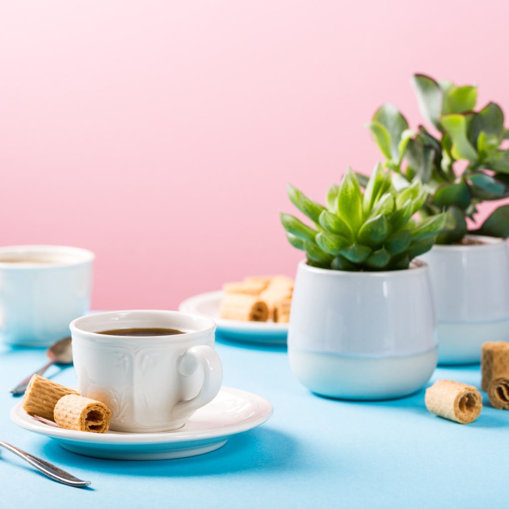 Чашка кофе на блюдце с вафлями на столе с цветами