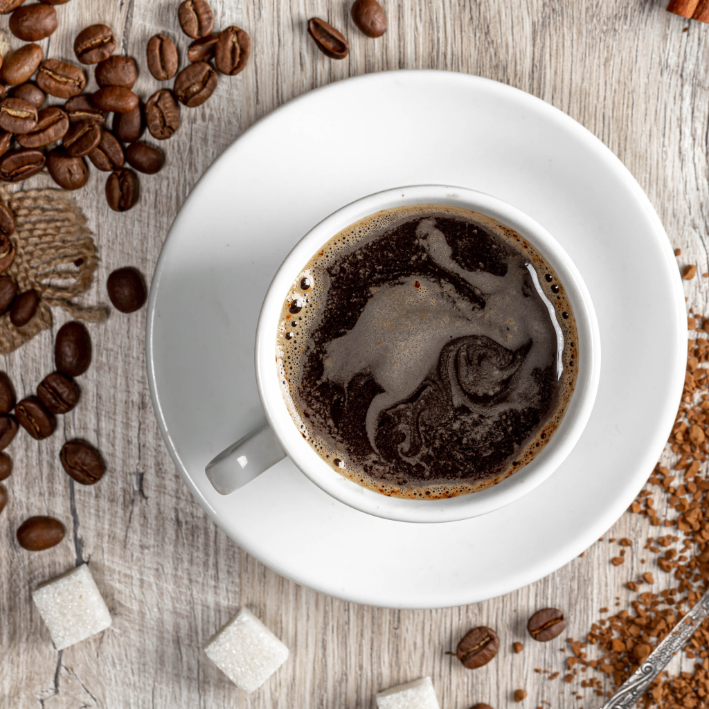 Чашка кофе на столе с сахаром и кофейными зернами