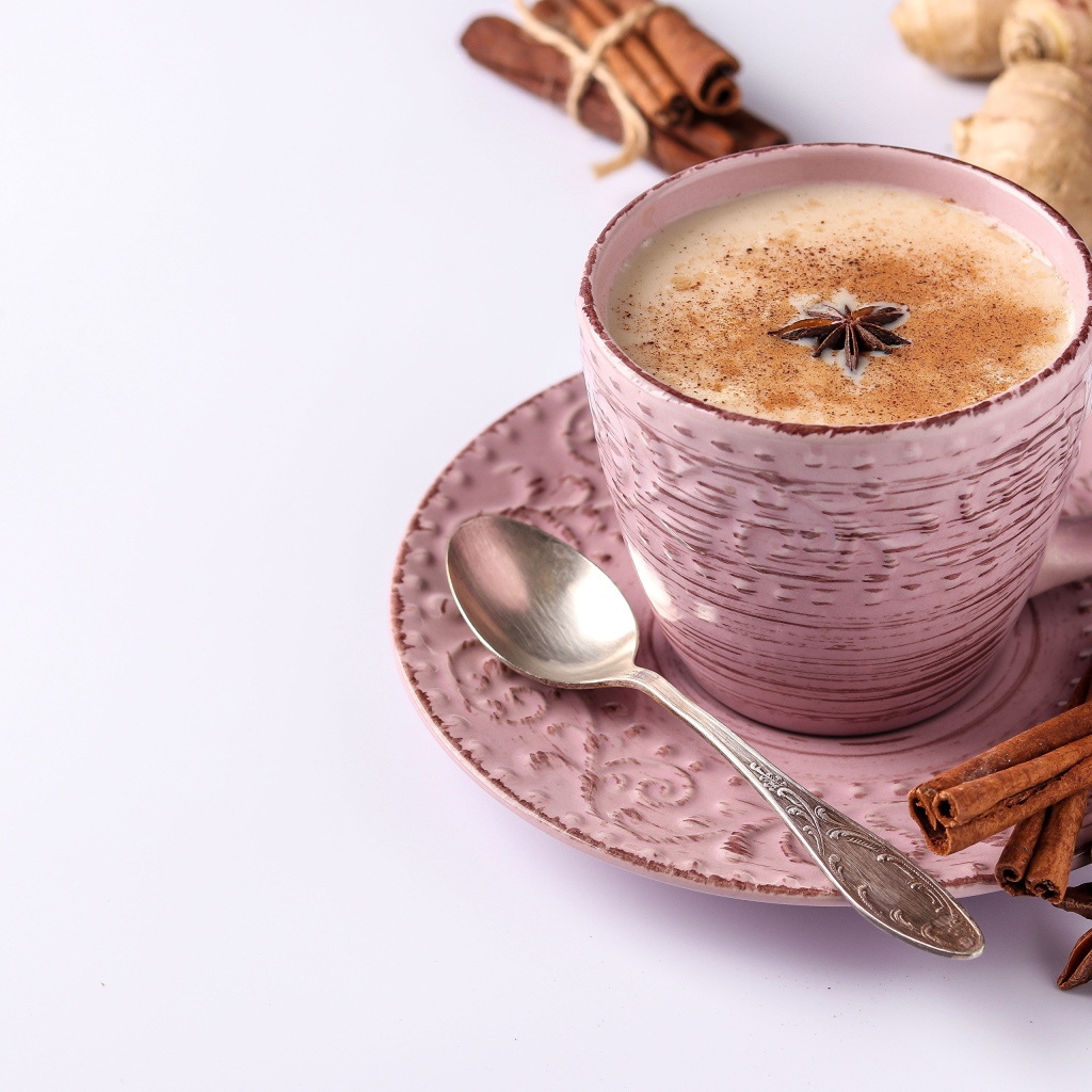 Чашка кофе на столе с корицей, бадьяном и  имбирем на белом фоне 