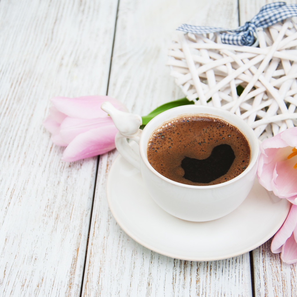 Чашка кофе на столе с розовыми тюльпанами и плетеным сердцем