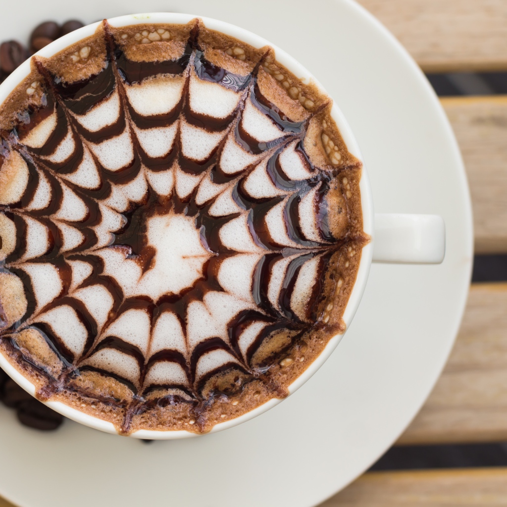 Чашка кофе с рисунком на пене на столе