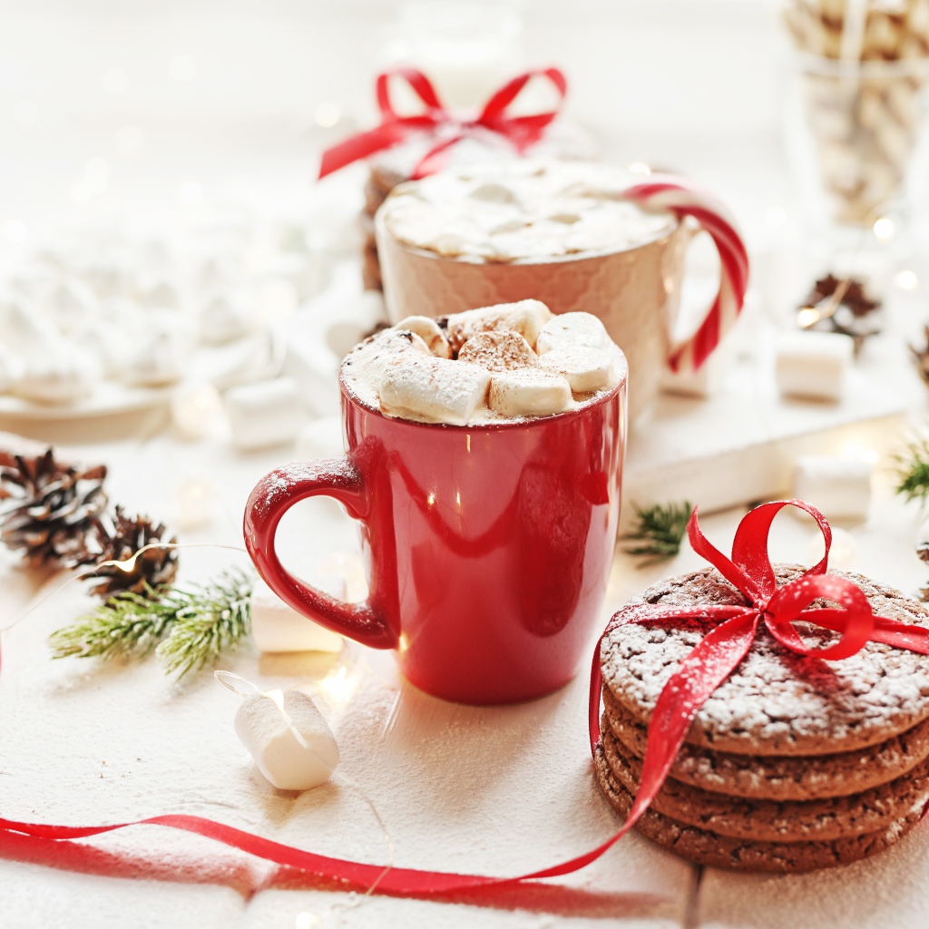 Чашки напитка с маршмеллоу на столе с печеньем