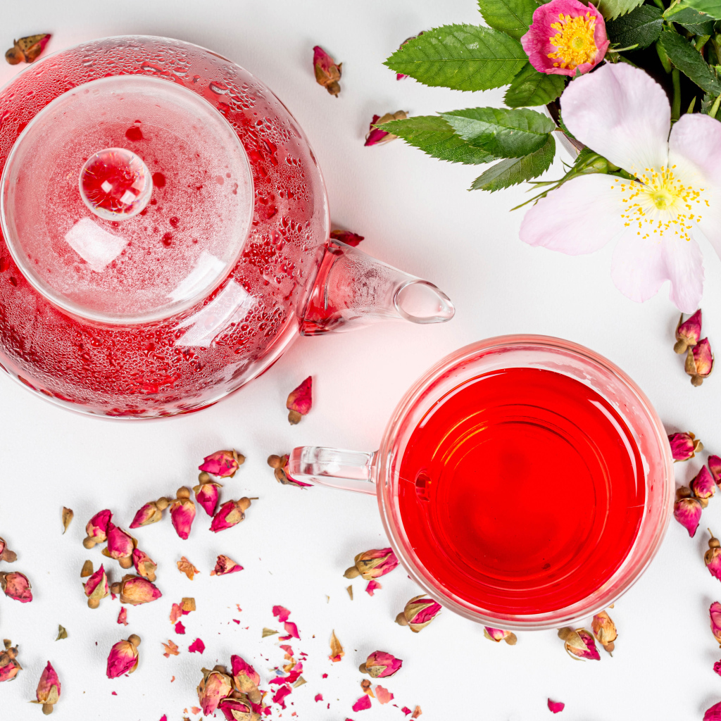 Свежий чай с шиповника в стеклянной чашке на столе с чайником