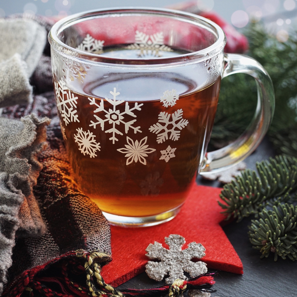 Стеклянная чашка чая на столе с ветками ели и шарфом 