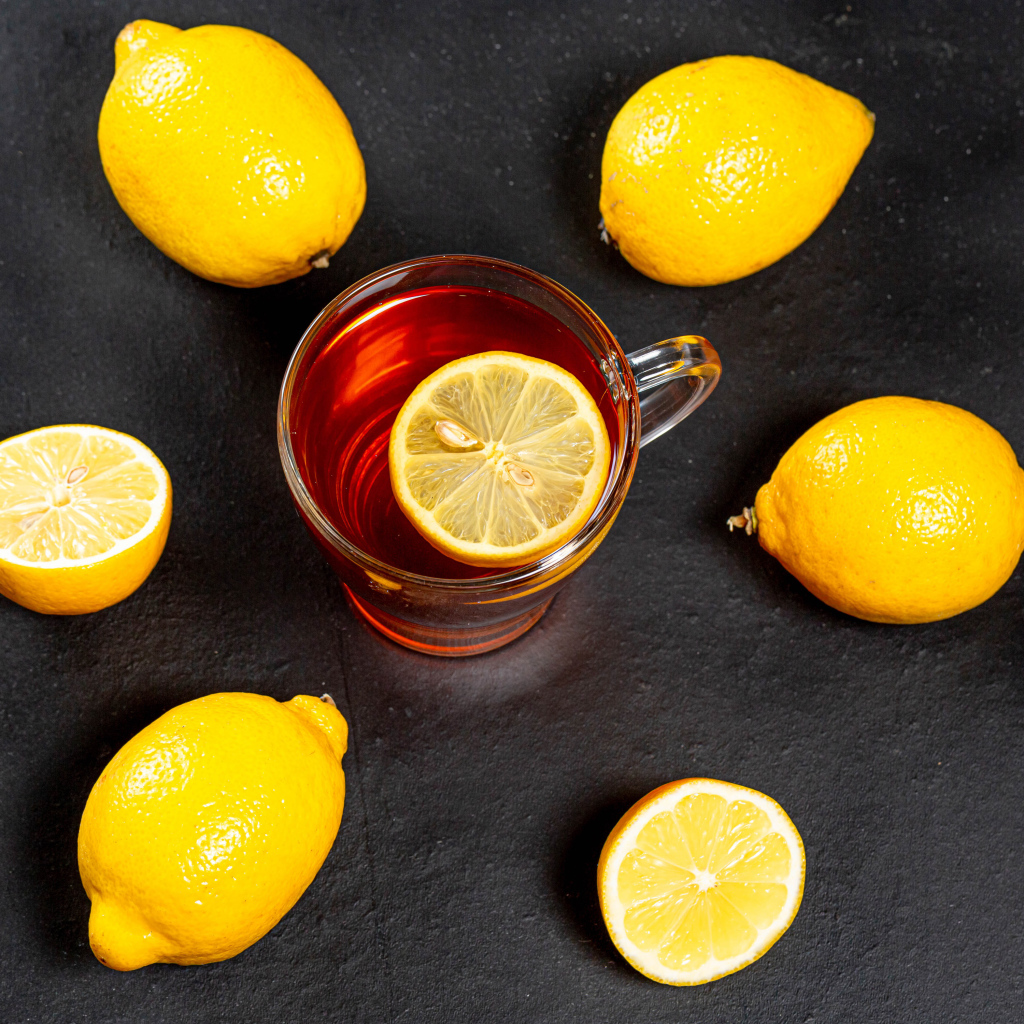 Стеклянная чашка чая с лимоном на сером столе 