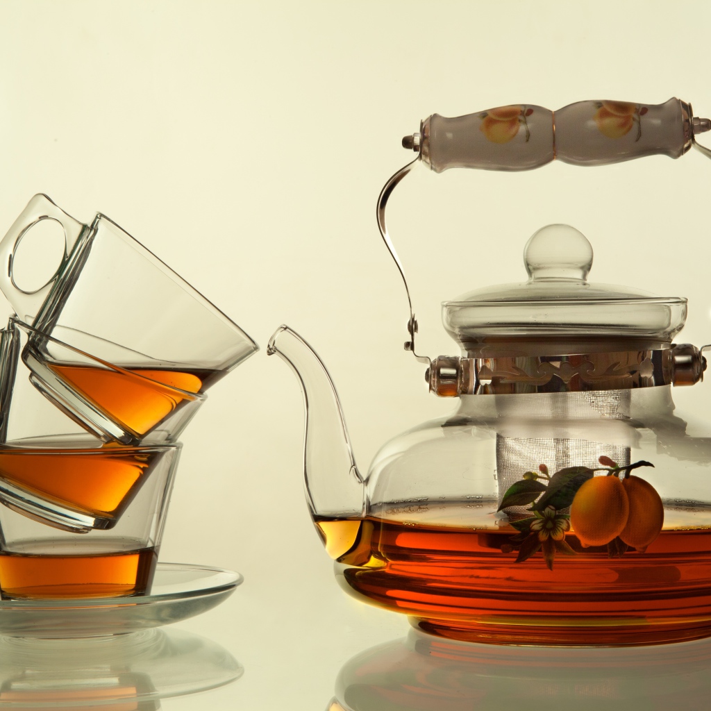 Стеклянный чайник с чашками на белом фоне