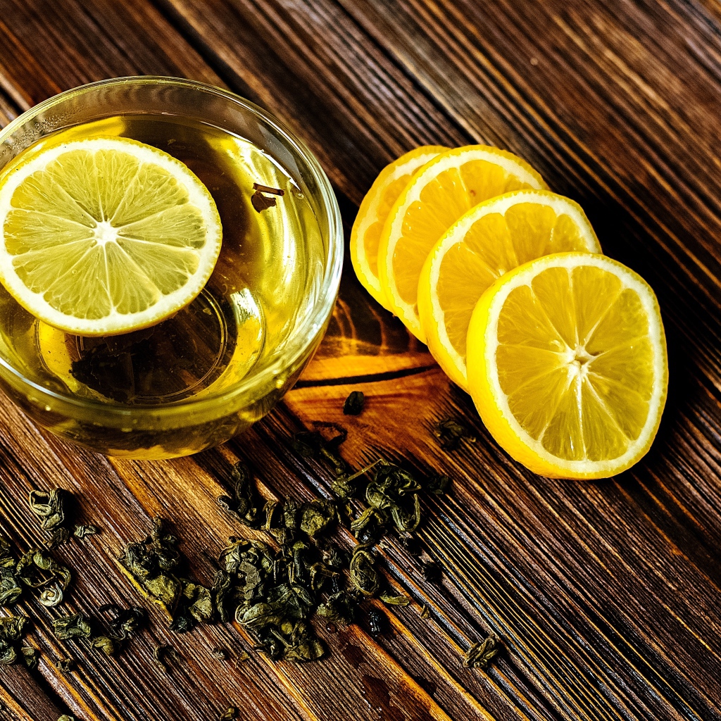 Зеленый чай в стеклянной чашке на столе с лимоном 