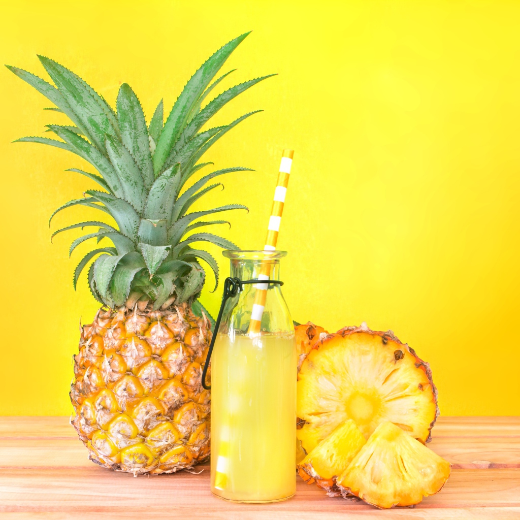 Сок в бутылке на столе с ананасами