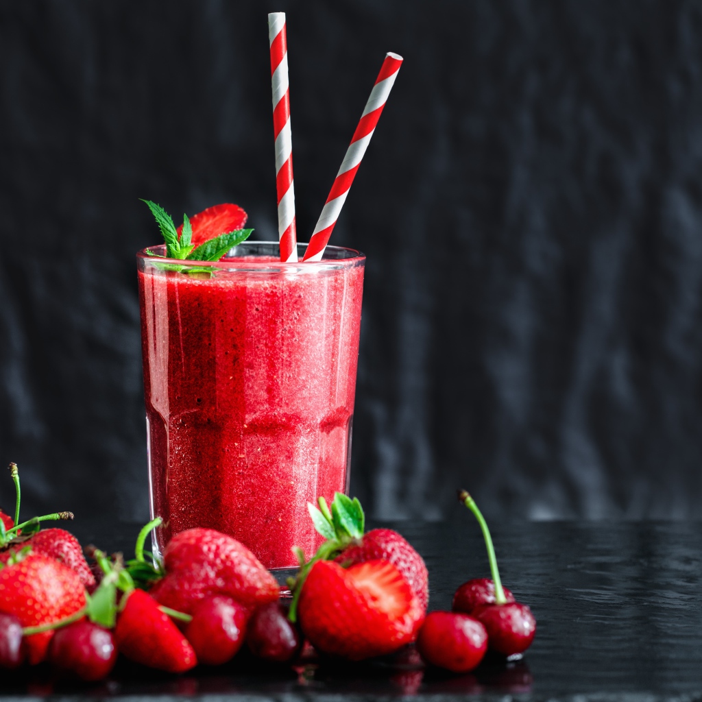 Смузи с ягодами клубники и вишни на столе