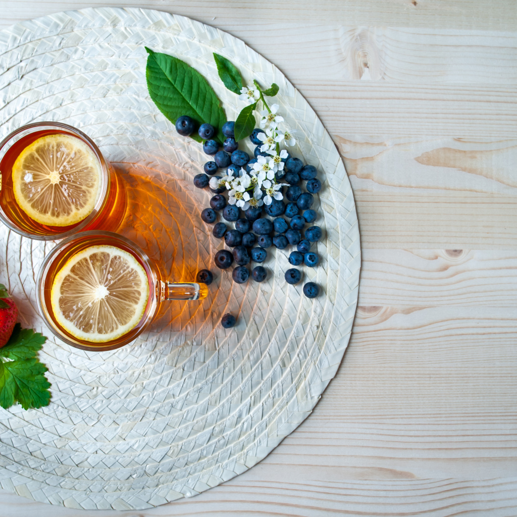 Чай с лимоном на столе с ягодами клубники и черники