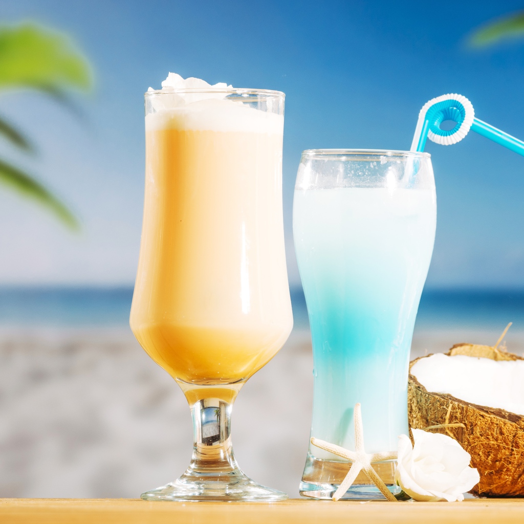 Два коктейля с кокосом на столе на тропическом пляже
