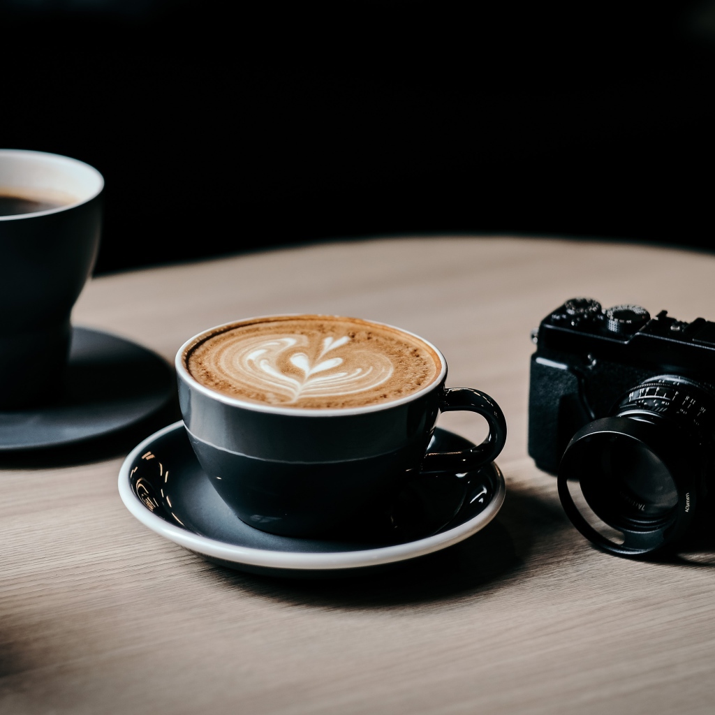 Две чашки кофе на столе с фотоаппаратом 