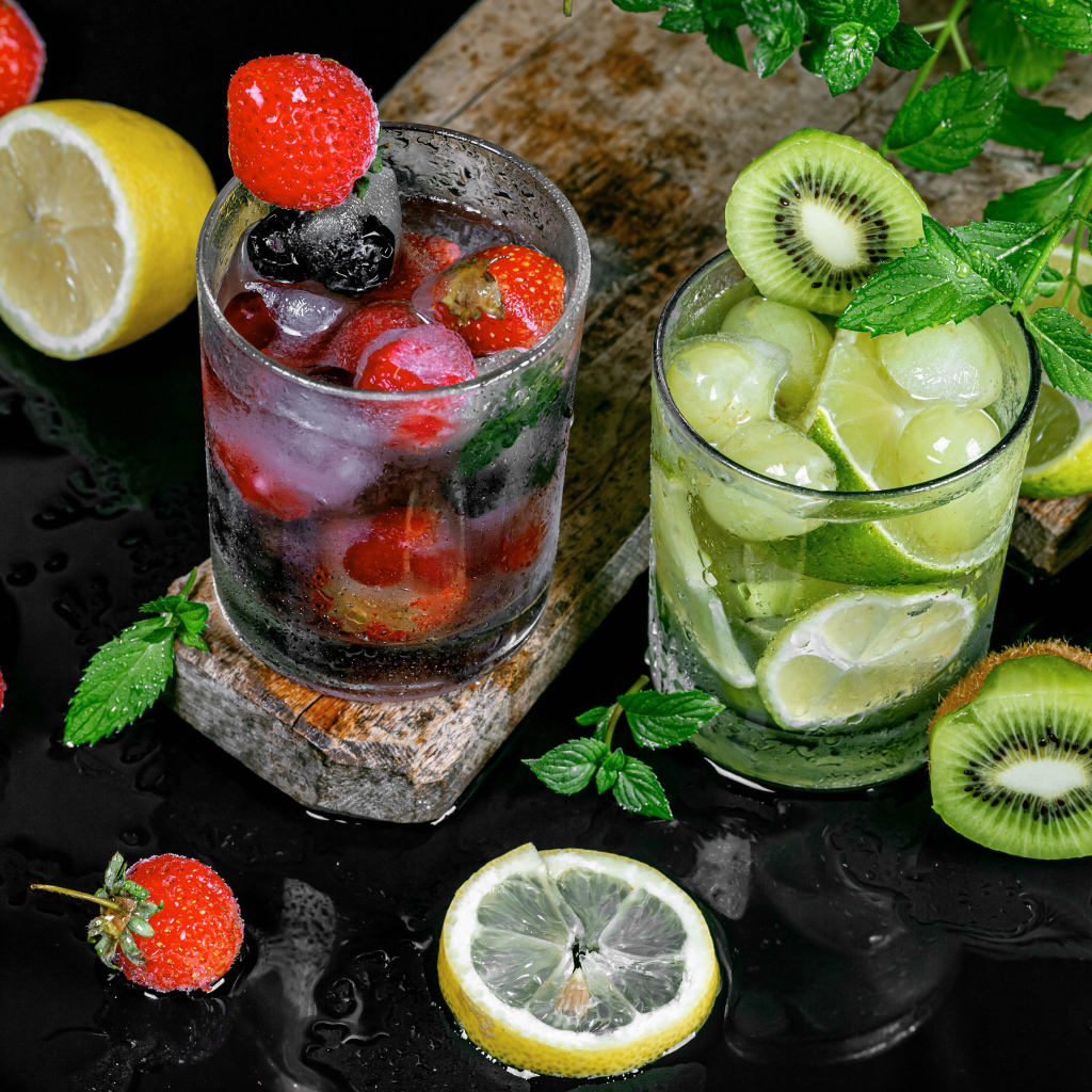 Два стакана мохито на столе с мятой, лимоном и клубникой 