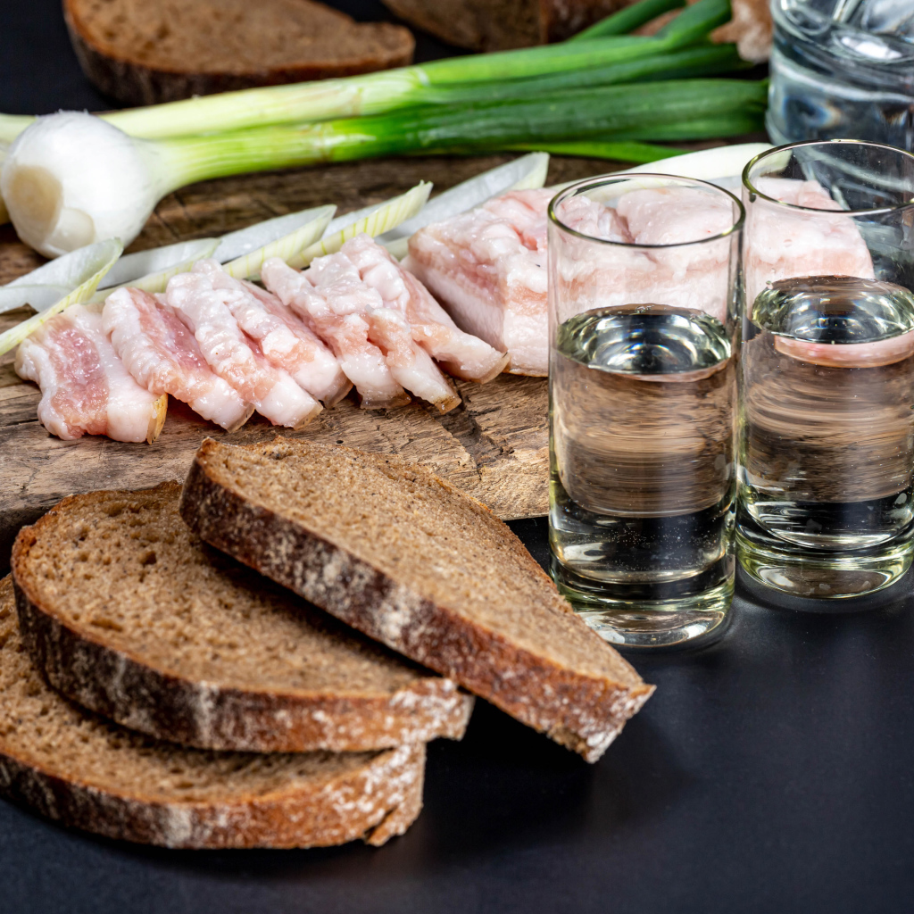 Две рюмки водки на столе с аппетитной закуской 