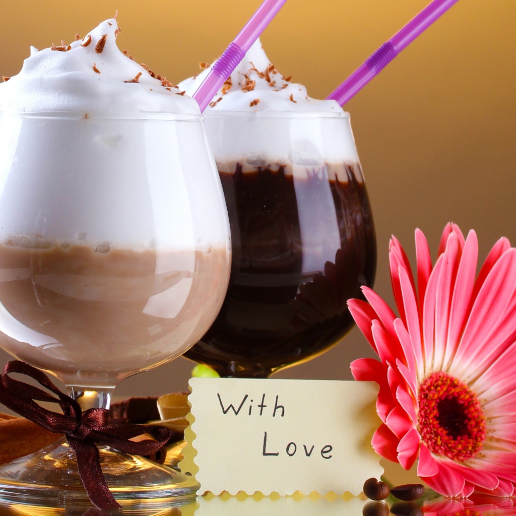 Два бокала с напитком на столе с розовой герберой