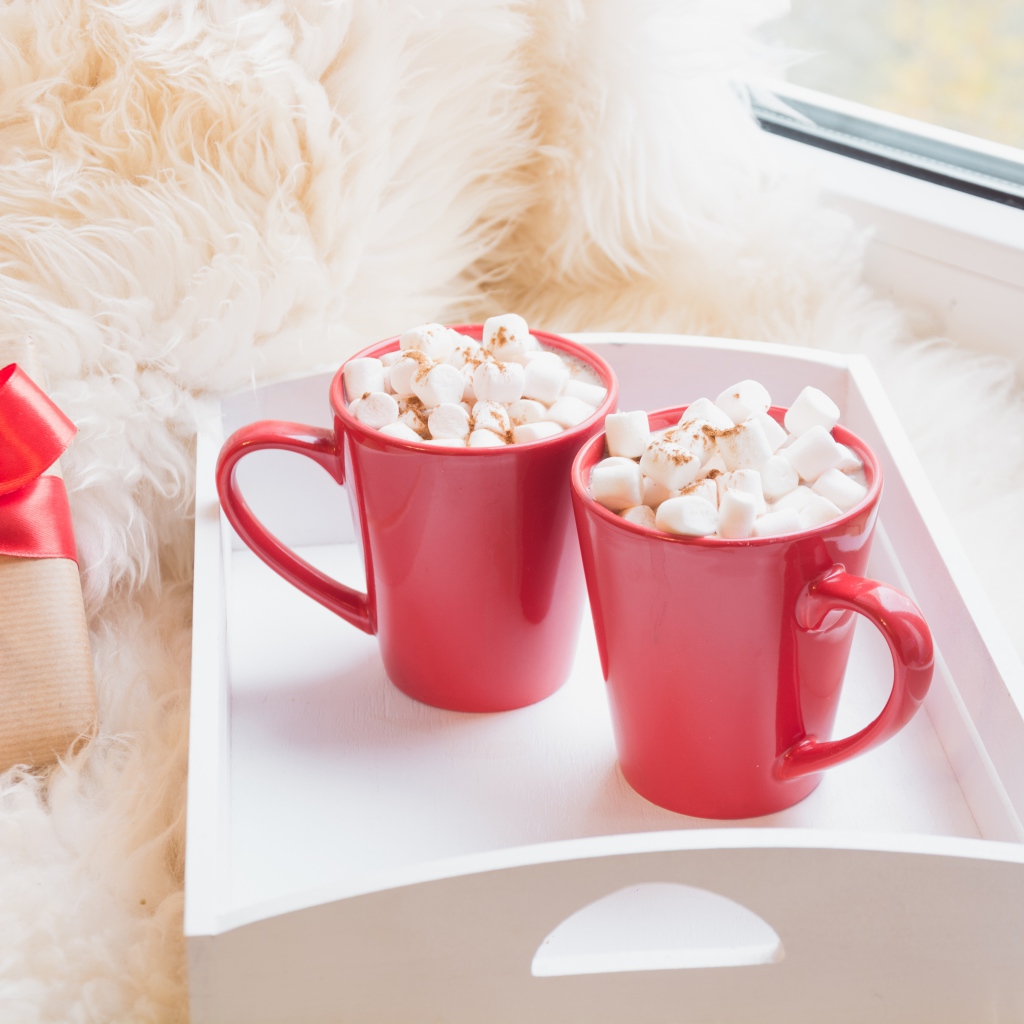 Две красные чашки с маршмеллоу у окна