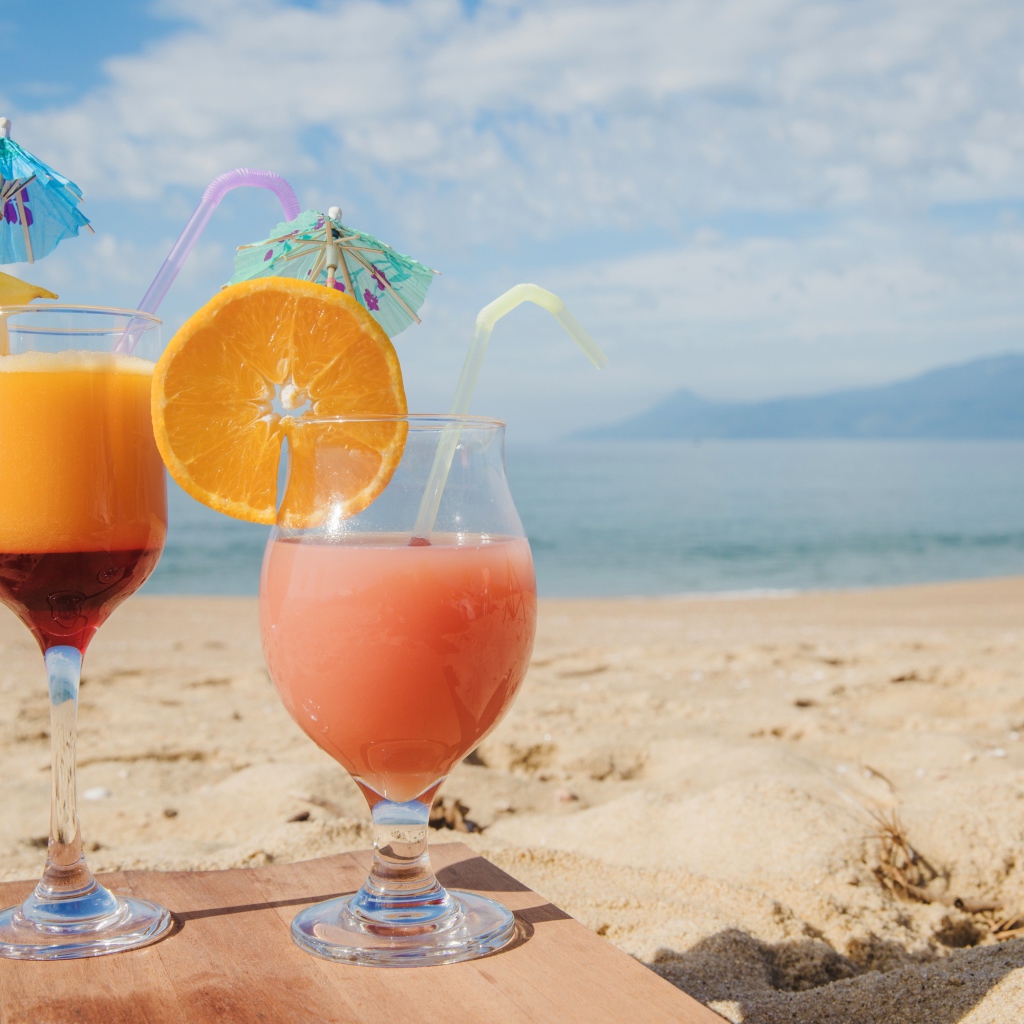 Два тропических коктейля на пляже в лучах солнца