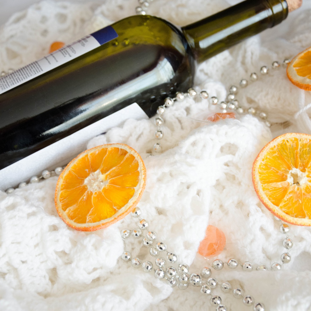 Бутылка вина и кусочки апельсина на белом платке 