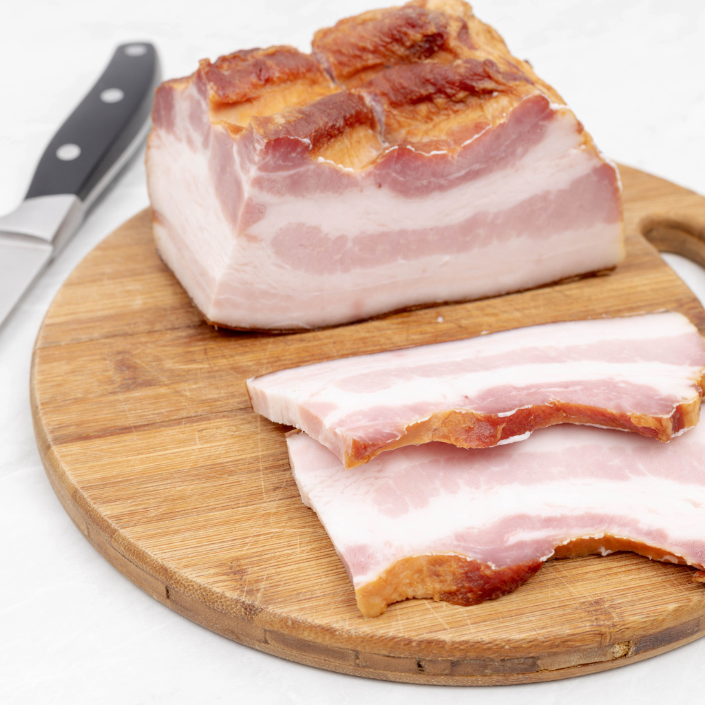 Кусок вкусного копченого сала на доске с ножом
