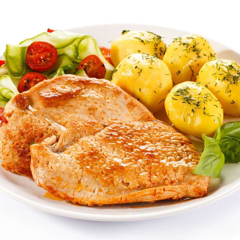 Кусок сочного куриного мяса на тарелке с картофелем и салатом