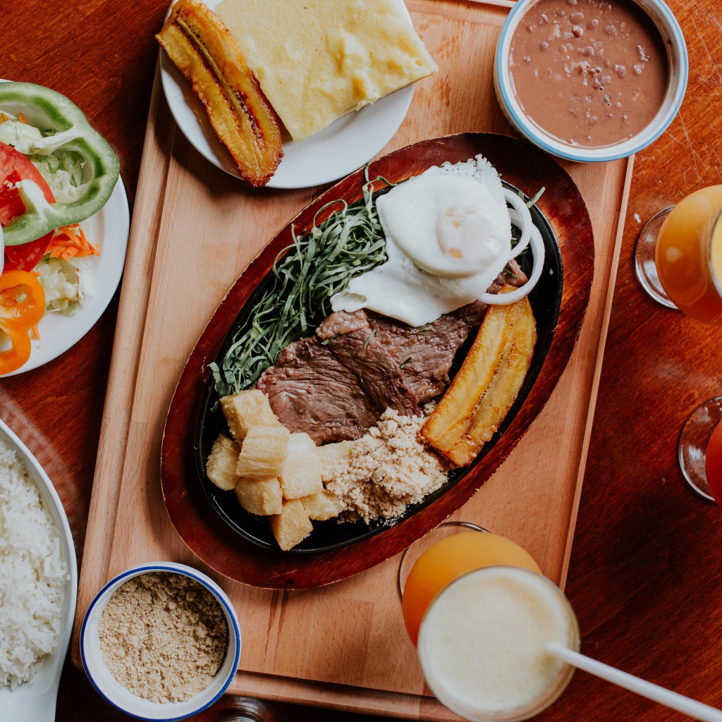 Кусок мяса в жаровне на столе с напитками, овощами и рисом