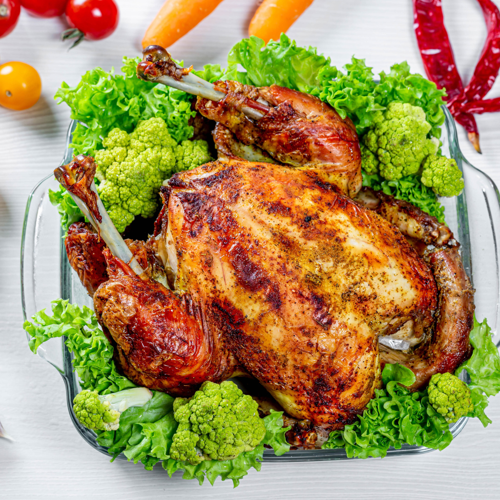 Запеченная курица с брокколи и листьями салата на столе с овощами