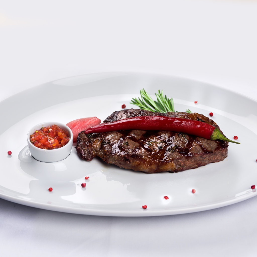 Стейк с кровью на тарелке с красным перцем