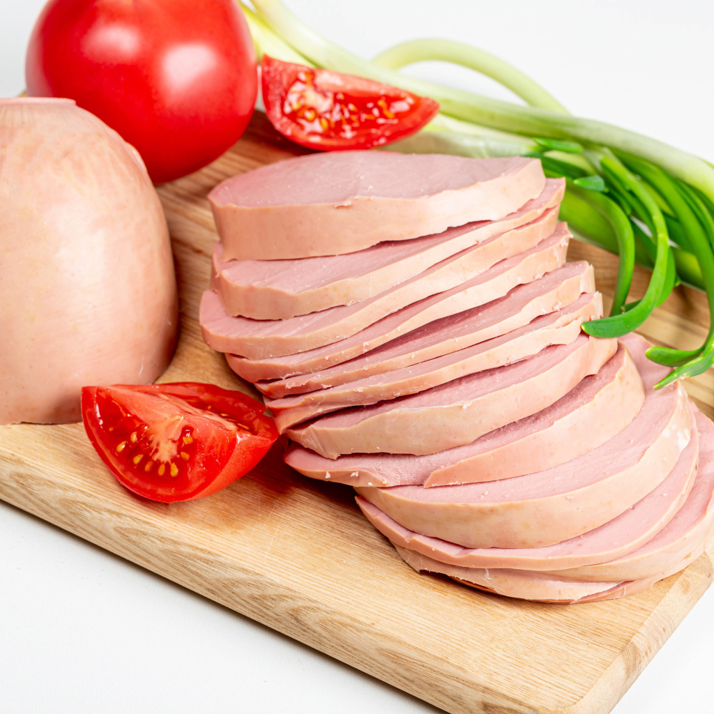 Вареная колбаса на доске с луком и помидором