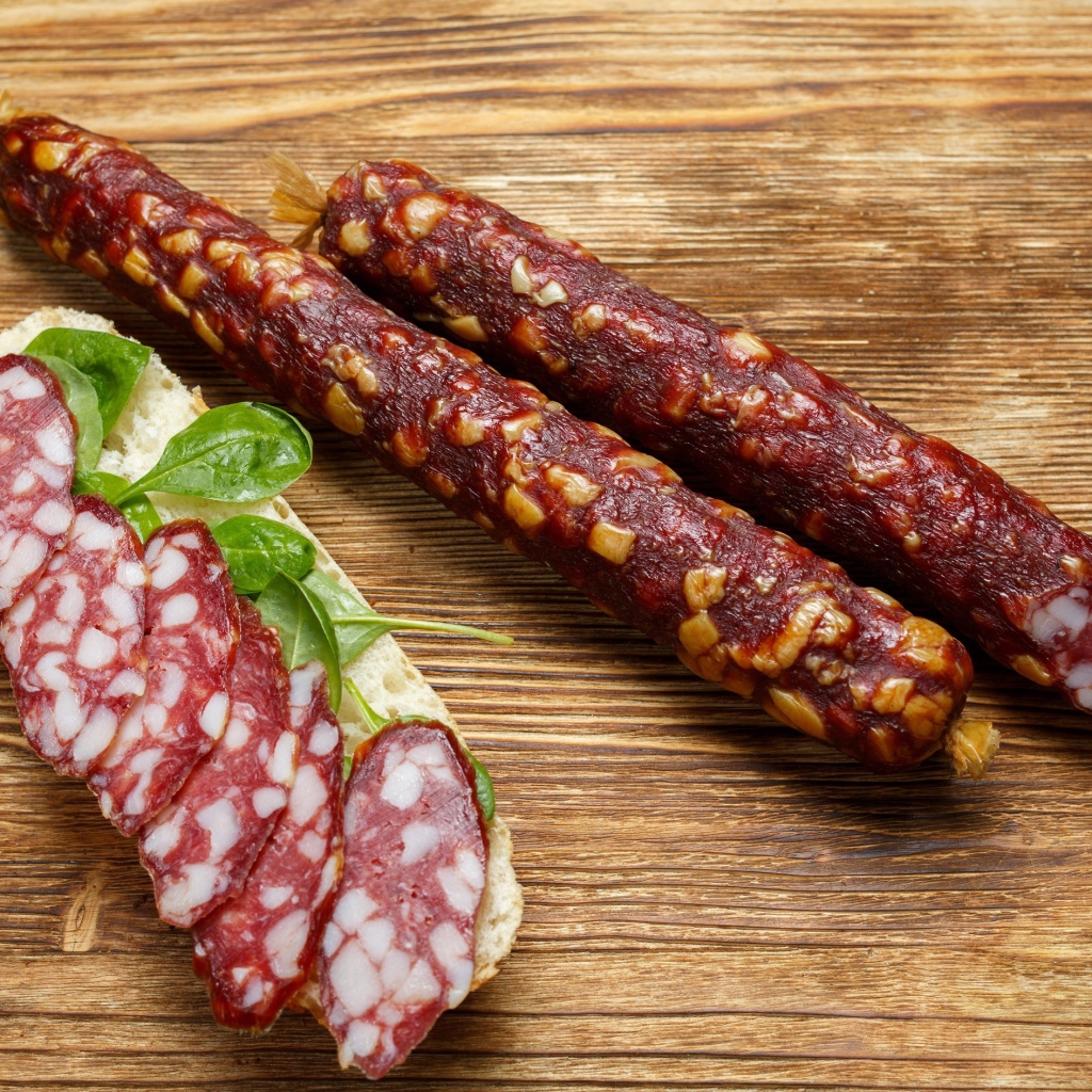 Вкусная сухая колбаса на столе с бутербродом