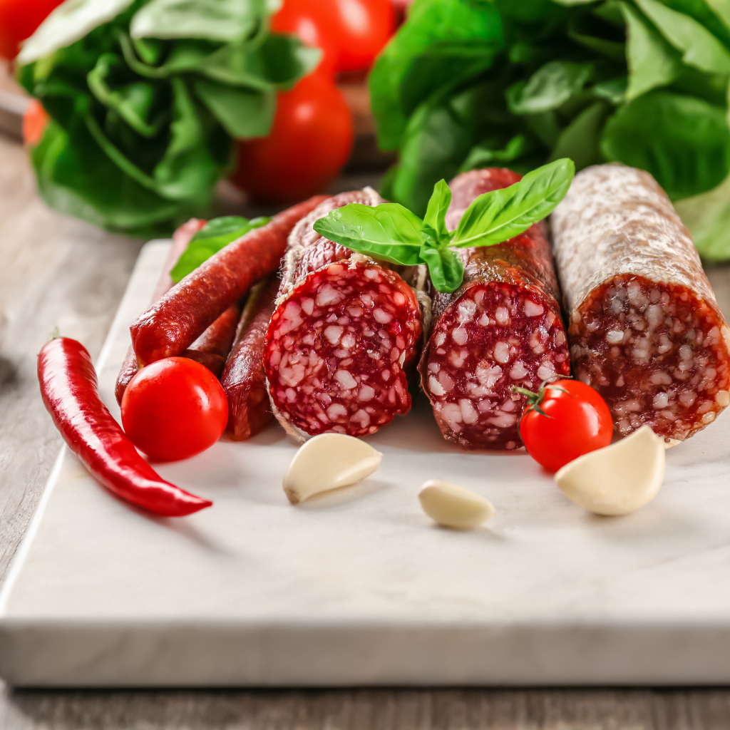 Вкусные колбасные изделия на столе с овощами