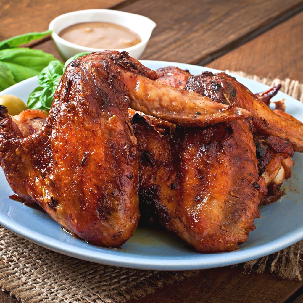 Зажареные куриные крылышки на столе с соусом и базиликом