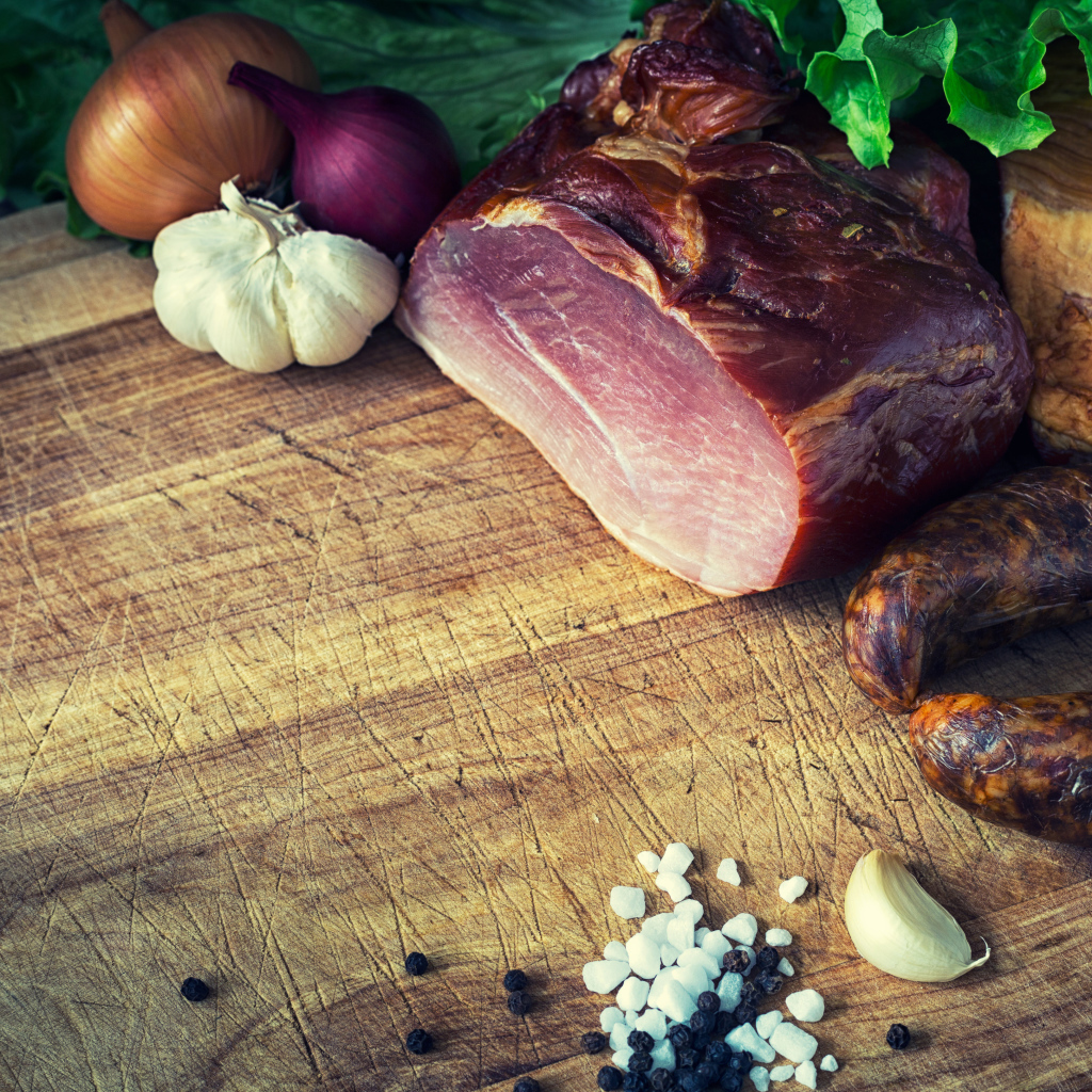 Мясные продукты на столе со специями, луком и чесноком 