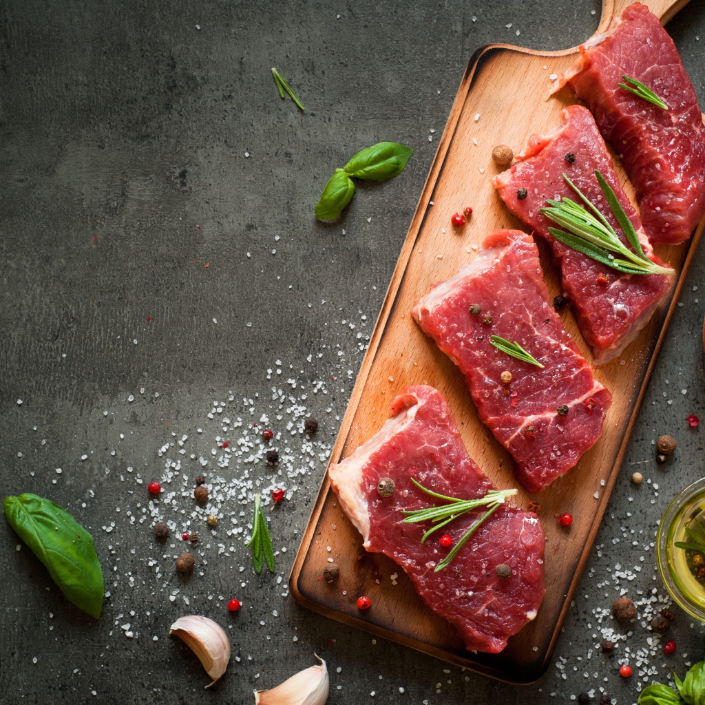 Куски мяса со специями и зеленью на доске 